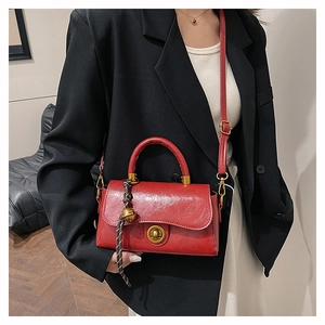 Close-up of red leather handbag with gold twist lock and woven bell charm detail