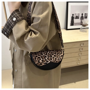 Detail of leopard print saddle bag with wide shoulder strap worn with a khaki trench coat