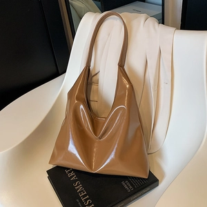 Minimalist brown patent leather shoulder tote bag placed on a book for office commute