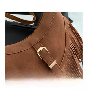 Close-up of brown suede shoulder bag featuring fringe tassels and metal buckle details
