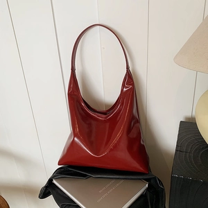 Minimalist glossy deep red hobo bag on books with warm lighting and a modern aesthetic