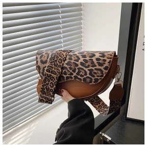 Detail view of stylish leopard print saddle bag with wide shoulder strap and gold hardware