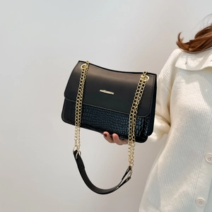 Black vintage shoulder bag with crocodile texture and gold chain strap shown on model