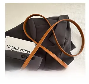Close-up of brown suede bag shoulder strap with fine stitching and metal lobster clasp