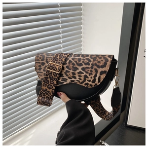 Detail of a leopard print saddle bag with wide strap and golden hardware accents