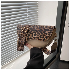 Detail of leopard print saddle bag with wide strap and gold hardware on window background