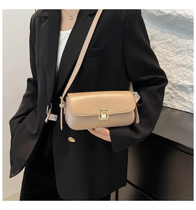 Détail du sac à bandoulière en similicuir beige avec fermoir en métal doré sur blazer