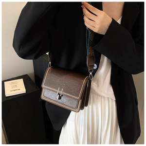 Detail of vintage dark brown crossbody bag with metallic rivets and wide jacquard strap