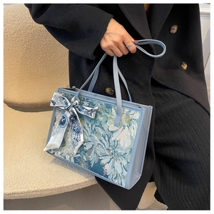 Détail d'un cabas jacquard bleu clair avec un nœud en foulard de soie sur la poignée