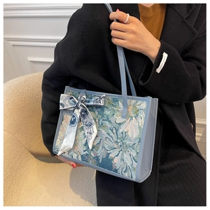 Détail du sac cabas jacquard bleu avec nœud en soie et poignées en cuir pour femme