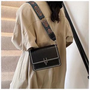Detail of black square crossbody bag with pearl trim and ethnic embroidered strap