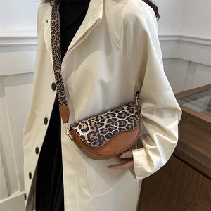 Stylish brown leather saddle bag with leopard print flap and wide crossbody strap