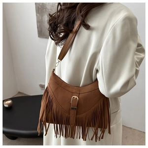 Close-up of brown suede crossbody bag with long tassels and vintage metal buckle detail