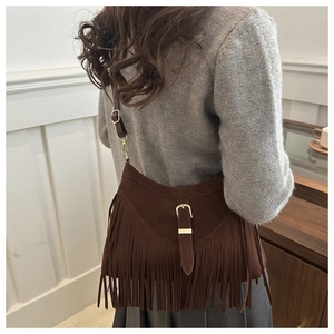 Close-up of bohemian dark brown suede bag with long tassels and vintage buckle strap