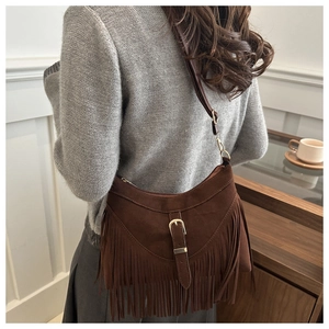 Detail of dark brown suede tassel bag with metal buckle and premium matte texture