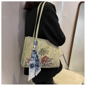 Détail d'un sac cabas en brocart floral orné d'un foulard en soie décoratif sur le côté