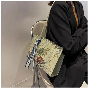 Détail de la broderie florale et du foulard en soie sur un sac fourre-tout vert