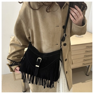 Detail shot of black suede crossbody bag featuring retro tassels and gold metal buckle