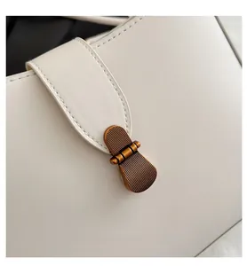 Close-up of vintage bronze vertical stripe buckle on beige leather crescent bag