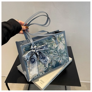 Détail du cabas en cuir bleu avec côté en tapisserie florale et foulard en soie décoratif