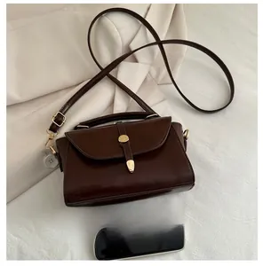 Deep brown vintage leather handbag shown next to a smartphone for size comparison