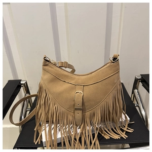 Detail of camel suede tote bag with long fringe accents and decorative buckle strap