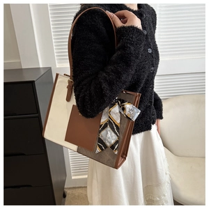 Detail of canvas tote bag with brown leather pocket and decorative silk scarf accent