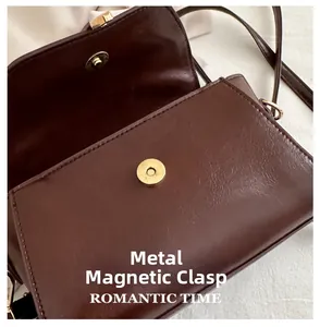 Macro detail of a magnetic golden hardware snap on a dark brown textured leather bag