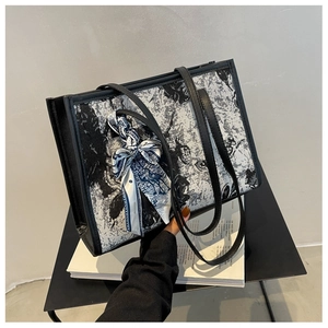 Détail du cabas en jacquard aux motifs floraux avec un foulard décoratif sur la poignée