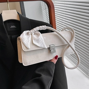 Chic beige shoulder bag with silk scarf handle and rhinestone buckle in fashion setting