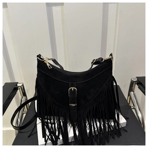 Detailed view of bohemian black suede crossbody bag with long tassels and gold buckle