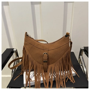 Detail of dark brown suede tassel bag with fringe and buckle in retro bohemian style