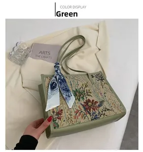 Gros plan du sac cabas en tapisserie fleurie verte avec foulard et finitions cuir
