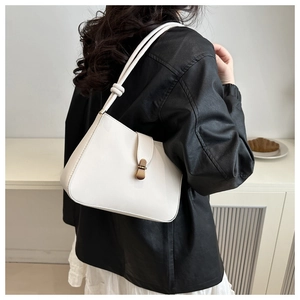 Detail of white crescent shoulder bag with vintage gold buckle and knot strap detail