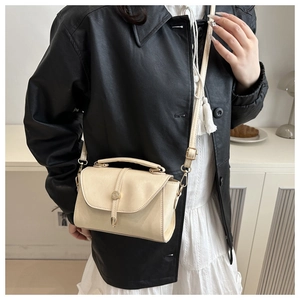Cream crossbody bag detail showing metallic bar closure and adjustable shoulder strap