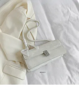 Detail of white leather shoulder bag featuring a silver rhinestone buckle and silk scarf
