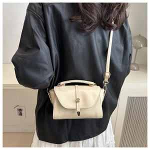 Cream vintage shoulder bag with metal buckle shown on model in black leather jacket