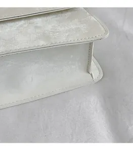 Detailed close-up showing the textured cream faux leather and precise stitching of the bag