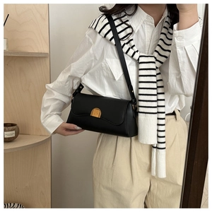 Detail of black faux leather half-moon shoulder bag with vintage gold metal buckle