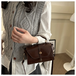 Brown vintage flap bag with gold hardware worn as a crossbody for daily style