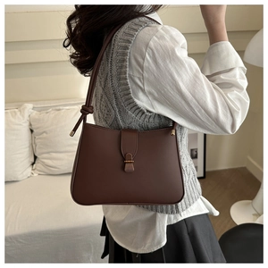 Detail of dark brown leather underarm bag featuring vintage gold clasp and knot strap