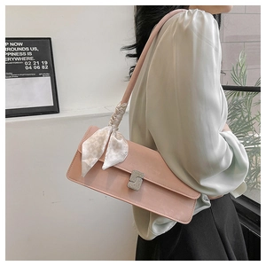 Detail of light pink shoulder bag featuring a rhinestone buckle and silk scarf decoration