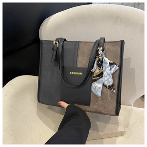 Minimalist large-capacity color-block tote bag with decorative silk scarf on a sofa