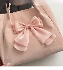 Detail einer rosa Seidentasche mit großer Schleife und geflochtenem Griff