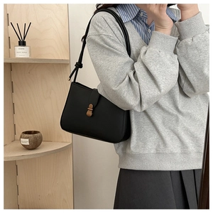 Detail of matte black leather underarm bag with gold metal buckle and shoulder strap