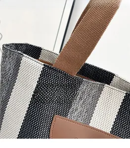 Close-up of precise stitching and texture on striped woven tote with leather detail