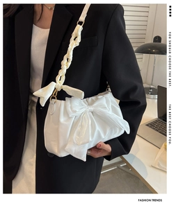 Detail of white pleated cloud bag with large bow and golden metal lobster clasps