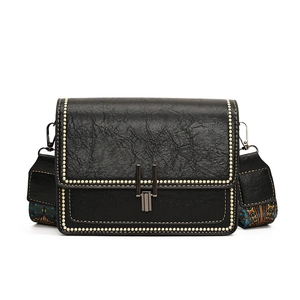 Retro black square crossbody bag with textured leather and printed strap on white background