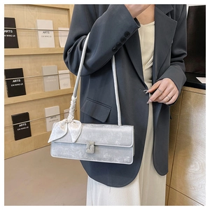 Detail view of silver gray textured shoulder bag with silk scarf and crystal buckle