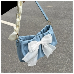 Detail of light blue pleated cloud bag featuring large white organza bow and silk handle